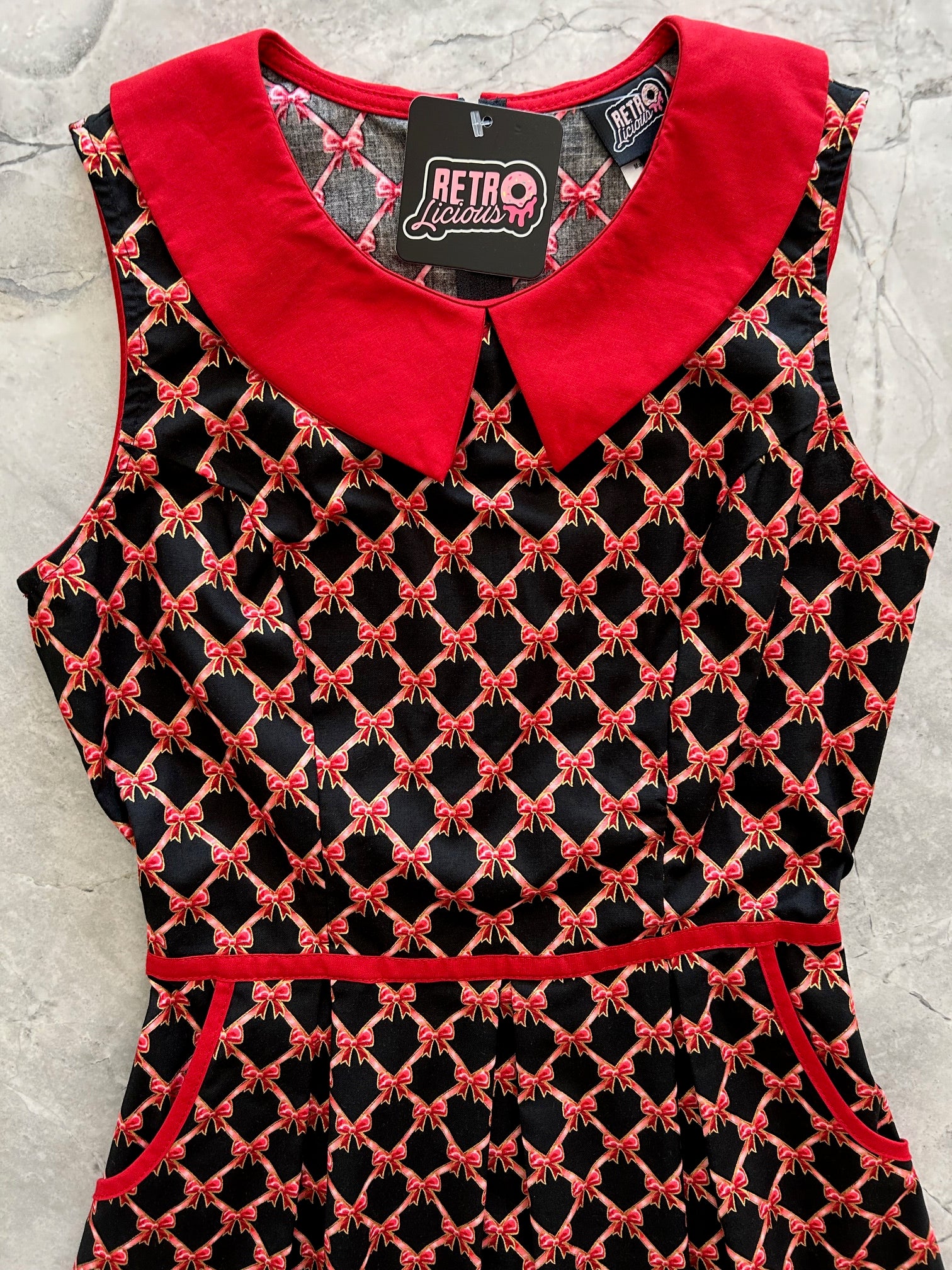 close up of bodice of bow collared dress showing red pater pan collar and red contrast piping on waist and pockets