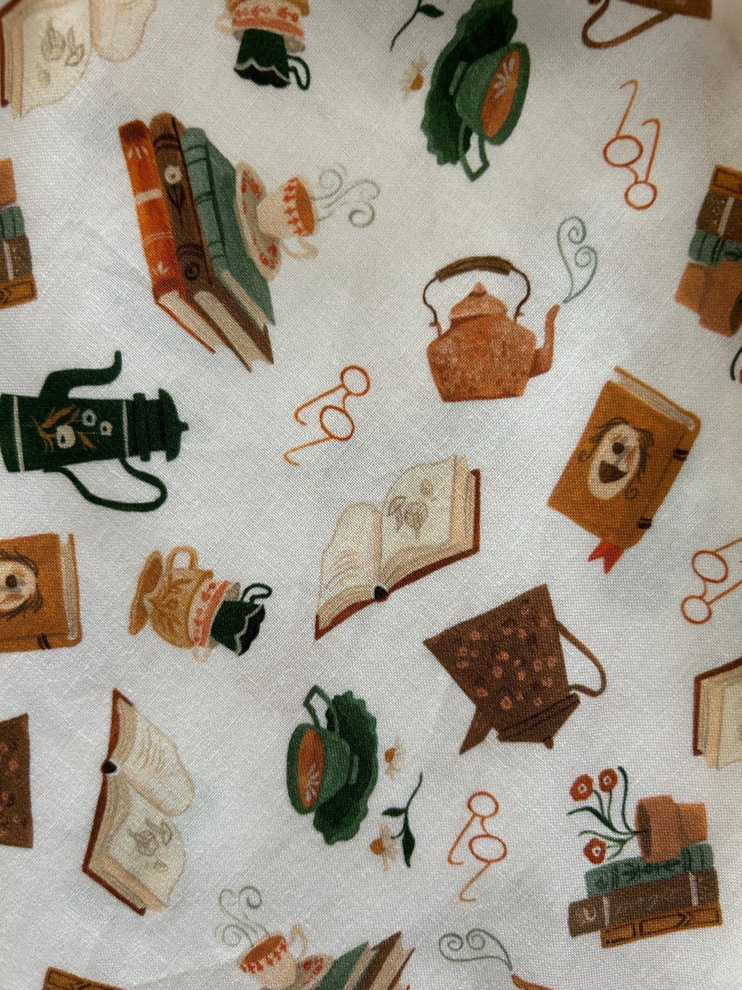 tossed print of books, teapots, glasses and more on creme colored backround