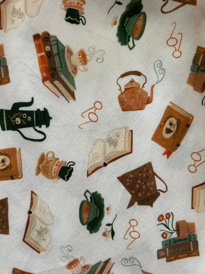 tossed print of books, teapots, glasses and more on creme colored backround