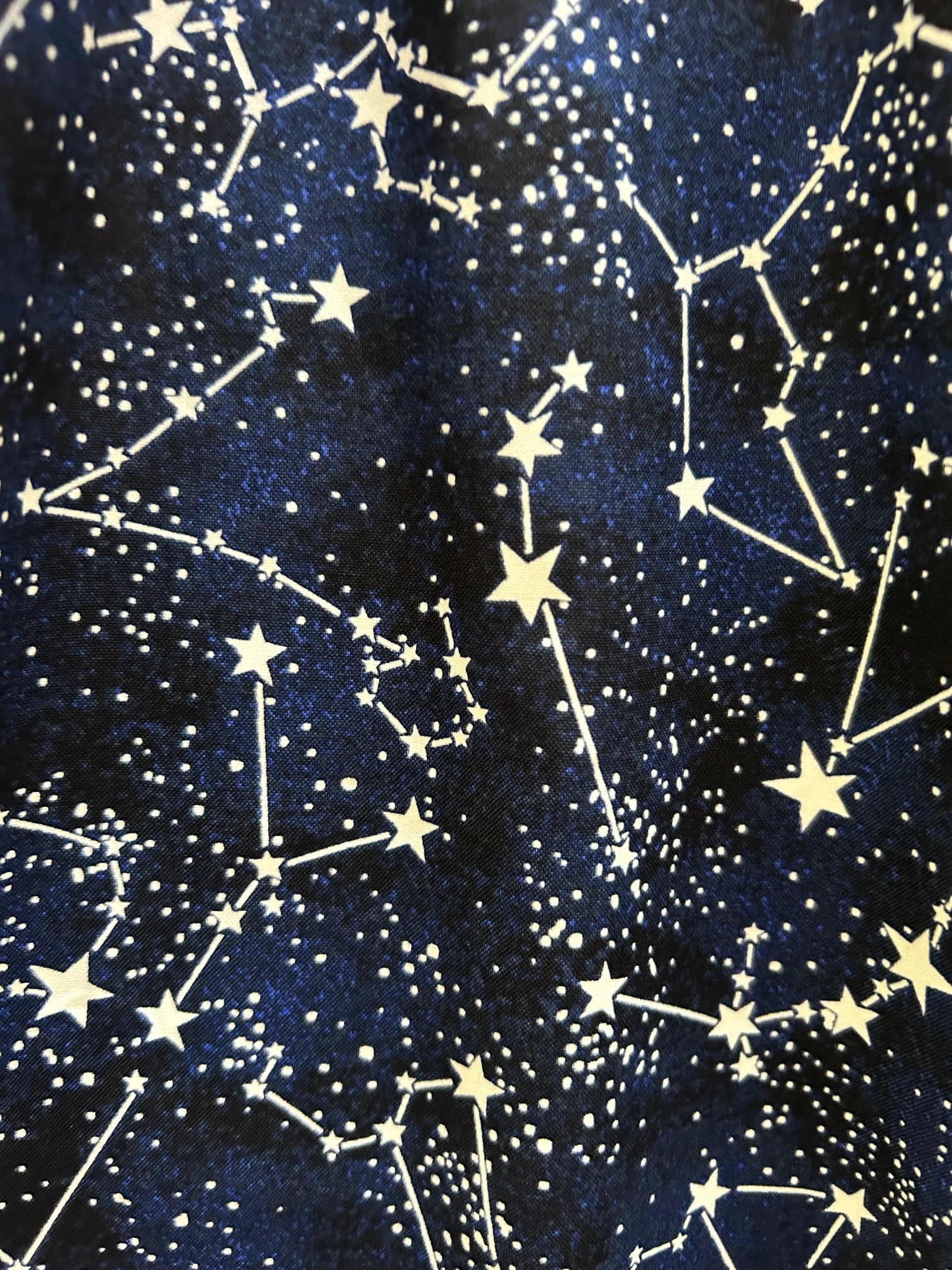 close up of fabric showing the constellations print on navy background