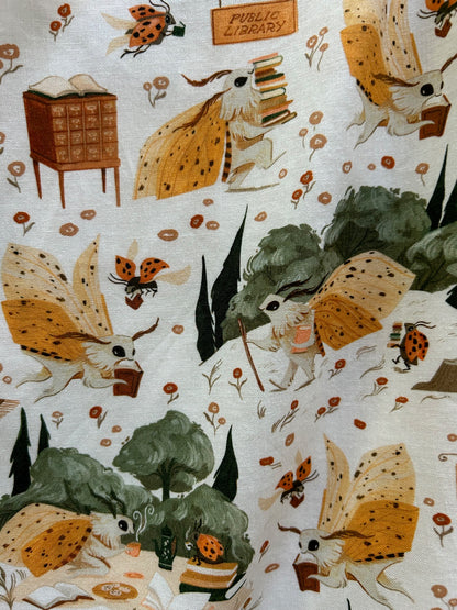 close up of novel nook print showing moths and ladybugs with books